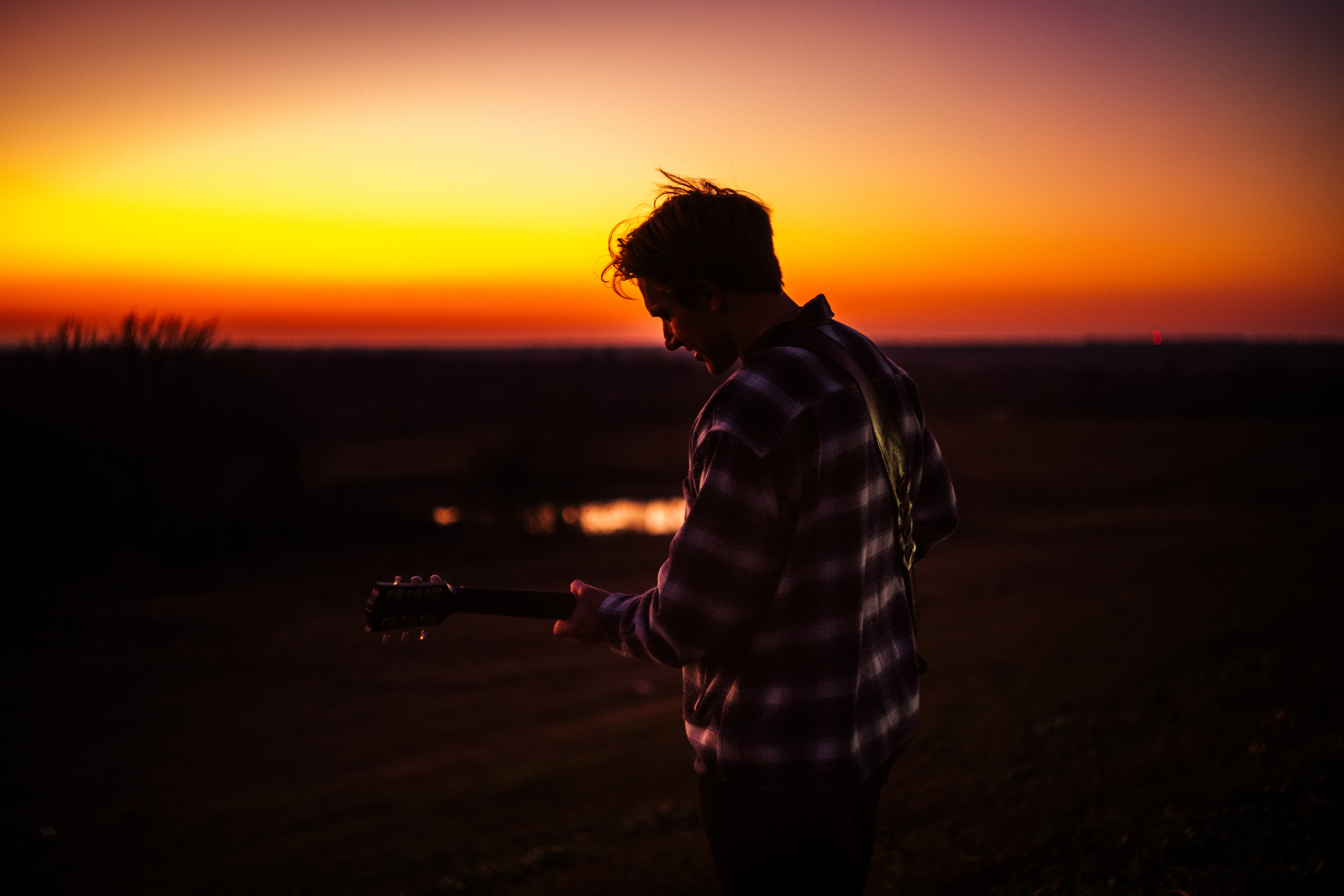 Nick standing and playing guitar at dusk